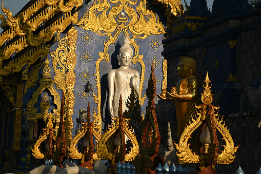 The back of the beauty blue chapel of Wat Rong Suea Ten temple have a large white Buddha image in the forbidding posture. Located Chaing Rai Province in Thailand.