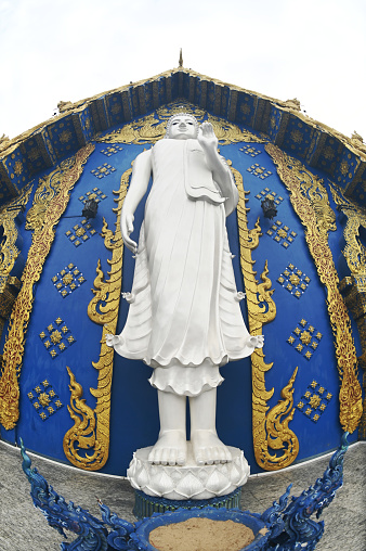 The back of the beauty blue chapel of Wat Rong Suea Ten temple have a large white Buddha image in the forbidding posture. Located Chiang Rai Province in Thailand.