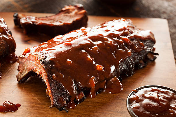 A close-up of smoked barbecue pork spare ribs on wood Smoked Barbecue Pork Spare Ribs with Sauce savory sauce stock pictures, royalty-free photos & images