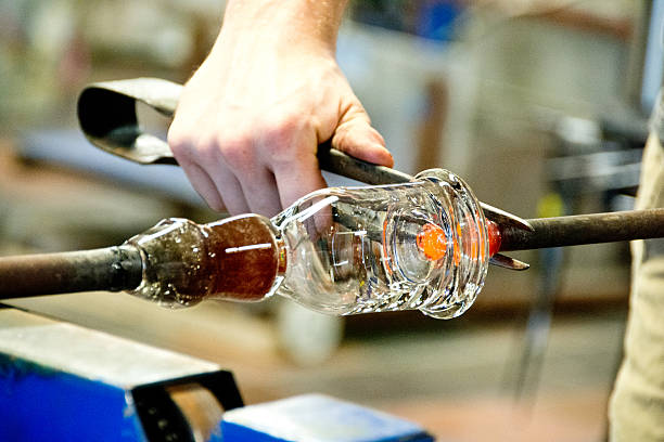 Trimming glass after blowing A worker trims excess glass from a glass that he has just blown. hand blown glass stock pictures, royalty-free photos & images