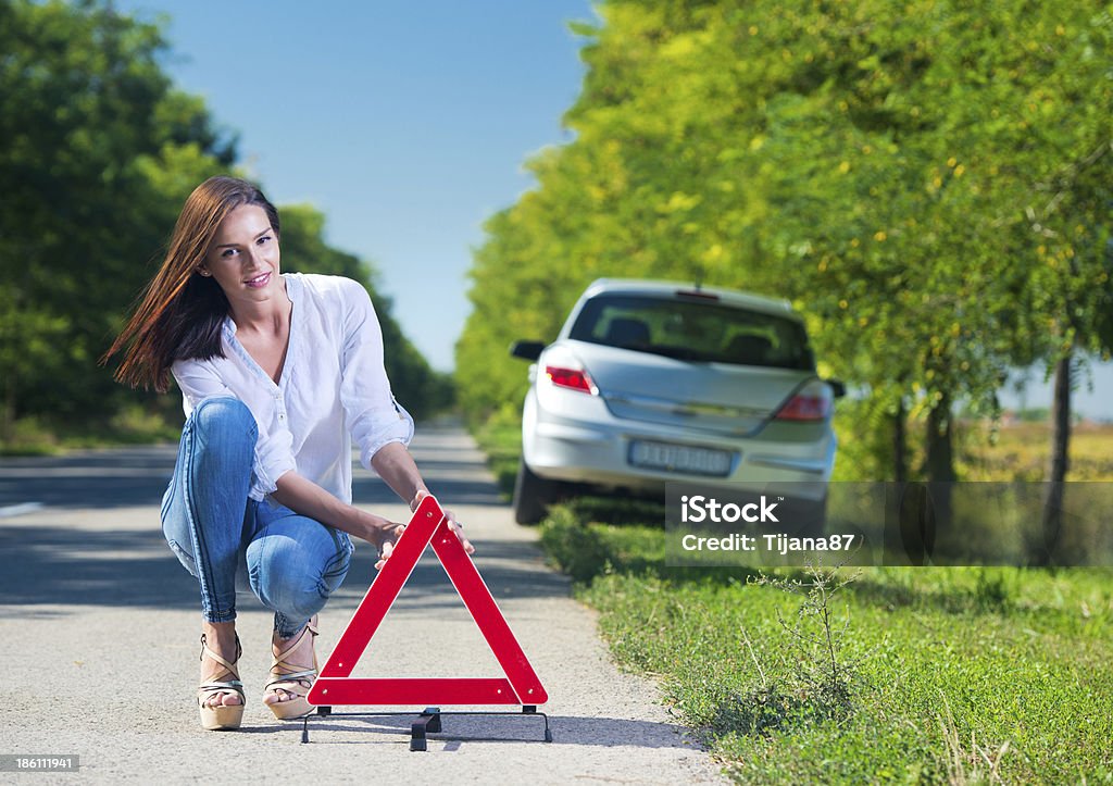 Femme mettant un triangle sur la route, car des problèmes - Photo de Danger libre de droits