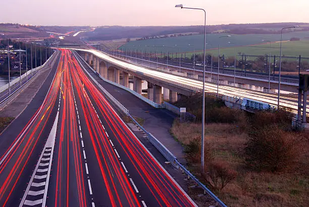Trails of light left by vehicles travelling at dusk on a motorway in England UK>