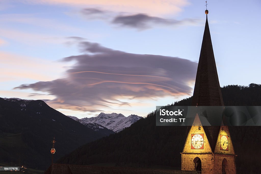 Church tower Lenticular cloud over the Alps with an illuminated church tower Architecture Stock Photo