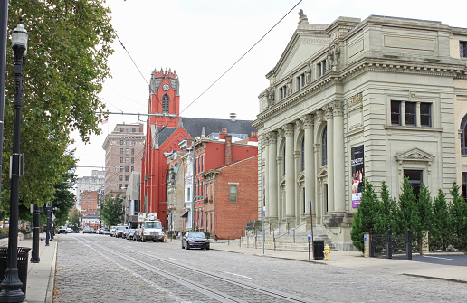 A view of downtown Cincinnati, Ohio with a cobblestone street, trolley tracks, and historic buildings