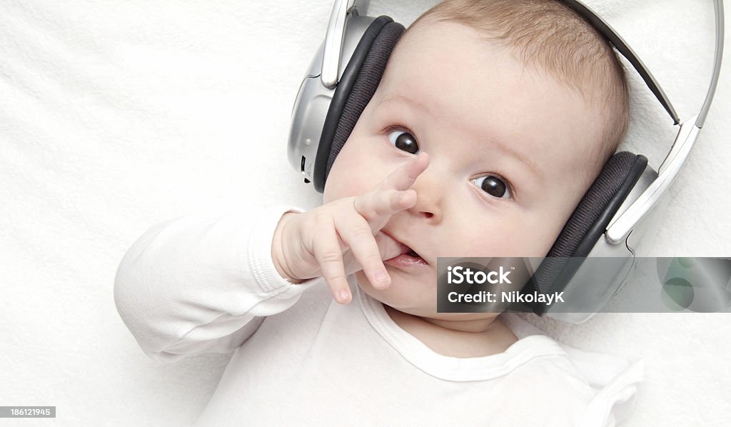 baby boy with headphone lies on back Baby - Human Age Stock Photo