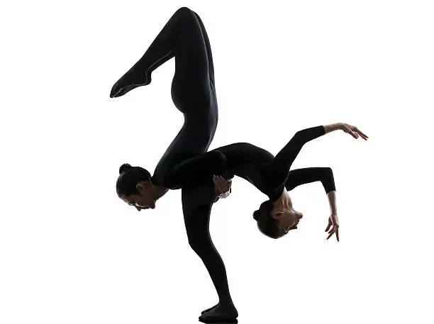 two women contortionist practicing gymnastic yoga in silhouette isolated on white background