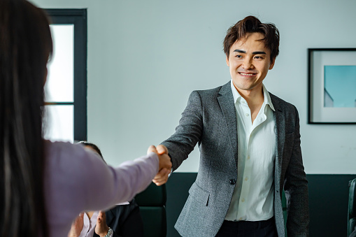 business person shaking hands during meeting in boardroom of modern office