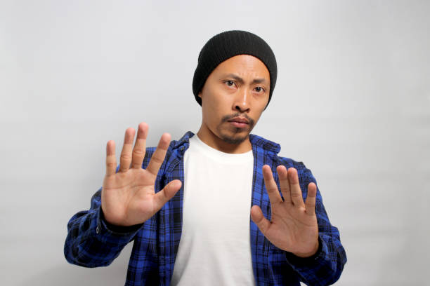 istock Young Asian man is pulling his hands away with palms facing outward, expressing refusal and denial 1861250715
