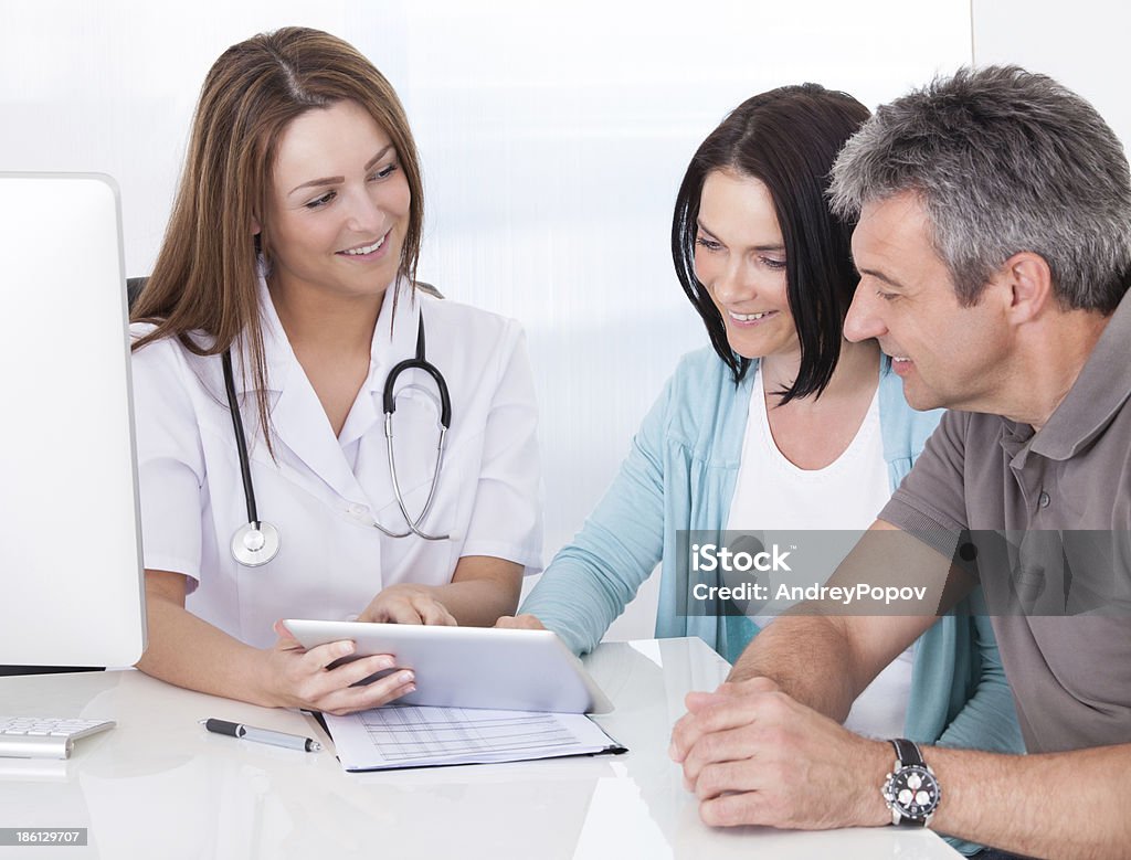 Doctor Showing Digital Tablet To Patient Happy Couple Looking At Digital Tablet Held By Doctor Adult Stock Photo