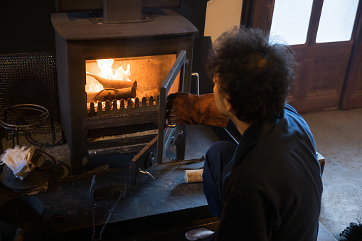 Japanese man putting wood in a wood stove in preparation for winter in rural Japan