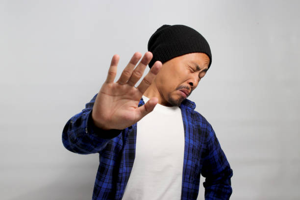 Displeased young Asian man wears a disgusted expression while visibly repulsed by something