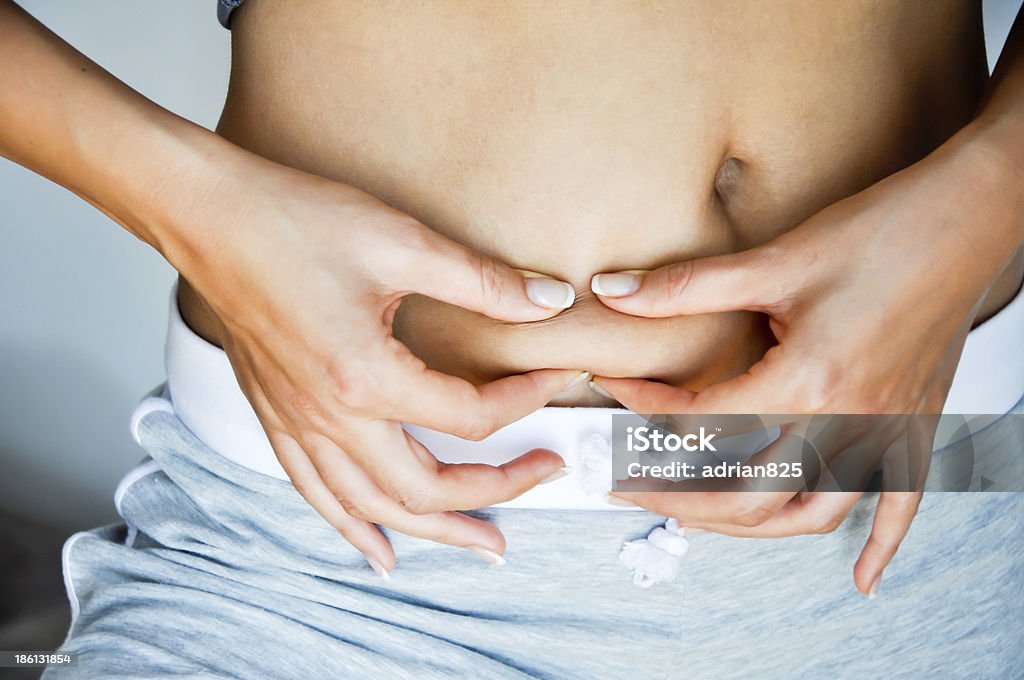 Woman with exposed belly pinching her belly fat woman with fat hips trying to lose weight African Ethnicity Stock Photo