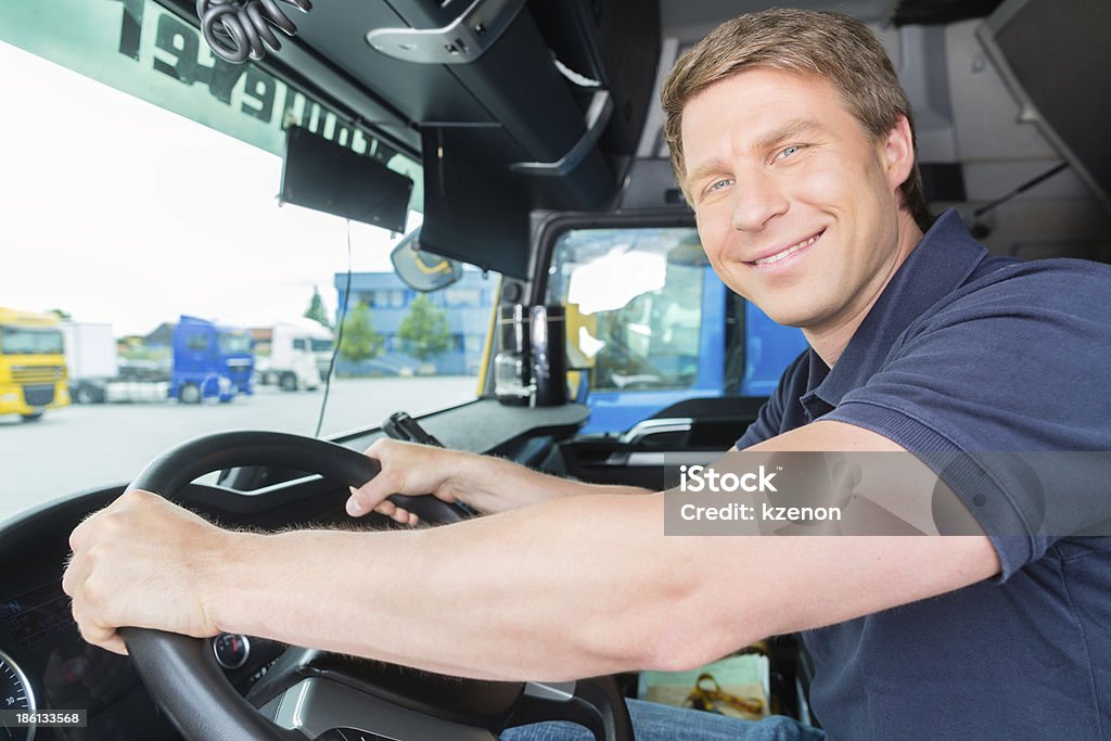 Forwarder or truck driver in drivers cap Logistics - proud driver or forwarder in drivers cap of truck and trailer, on a transshipment point Adult Stock Photo