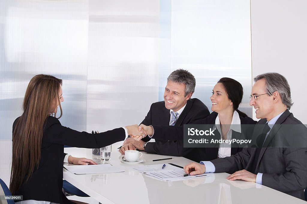 Two Businesswomen Shaking Hand Businessmen Looking At Business Women Shaking Hand Active Seniors Stock Photo