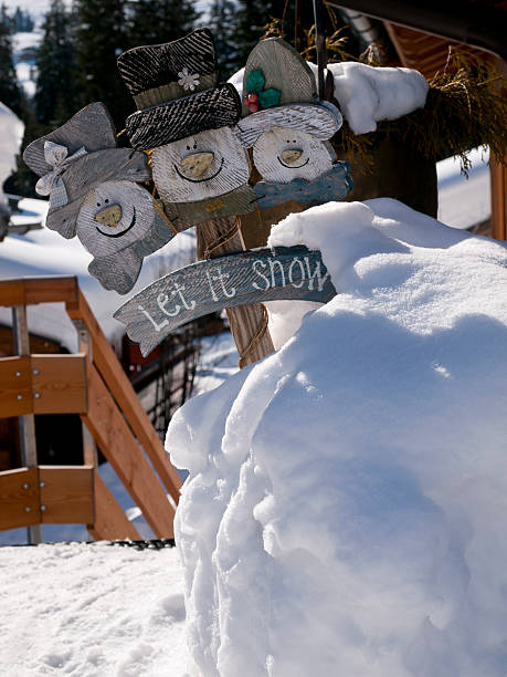 "let it snow" sign in a big pile of snow stock photo
