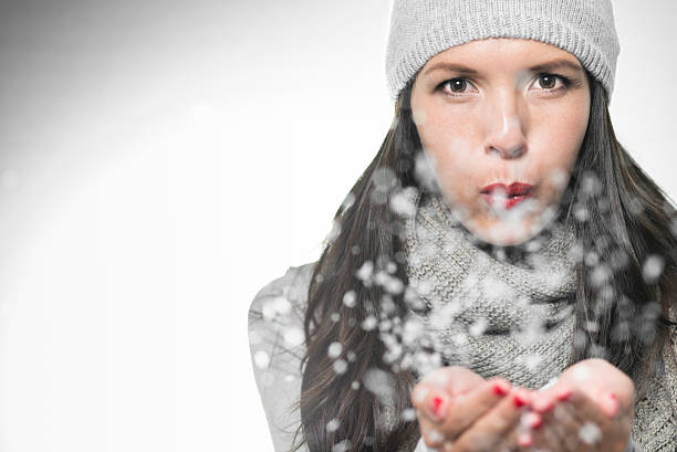 istock Attractive woman blowing snowflakes 186142455