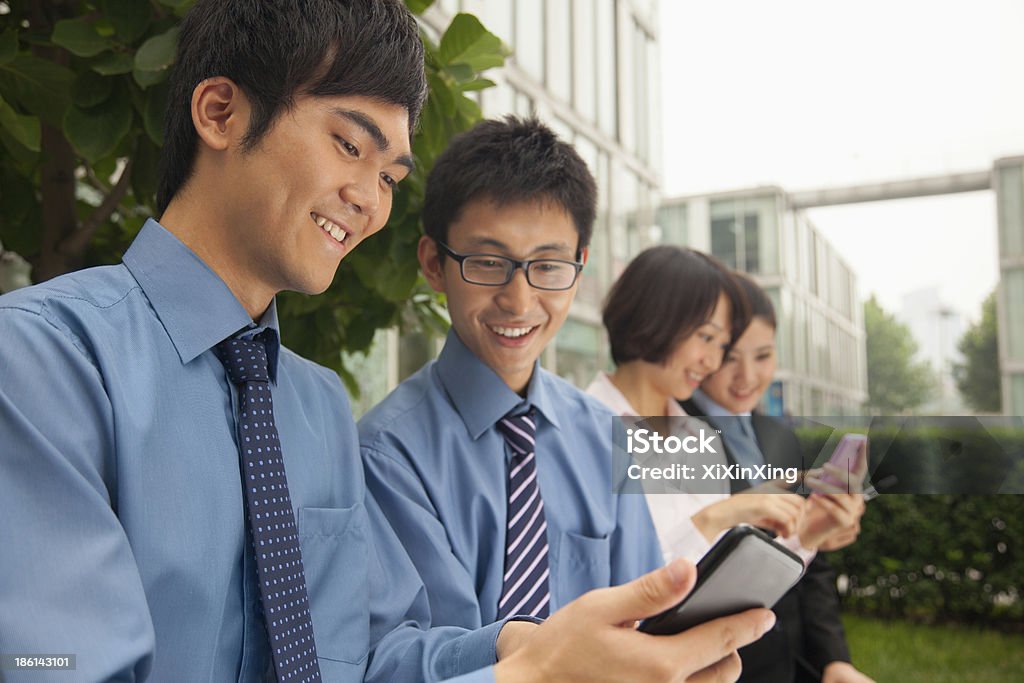 Young business people verificar sus teléfonos celulares - Foto de stock de 20-24 años libre de derechos