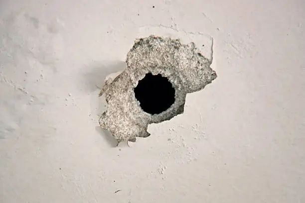 Bullet hole on the white wall.