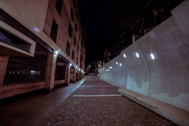 Captured on the night street in the Holyrood area of Edinburgh, the photograph invites viewers to explore the quiet charm of the night street, where the interplay of architecture and soft lighting creates a serene urban atmosphere.\n\nThe condo stands tall, its windows radiating warm light, while an adjacent wall is bathed in subtle illumination, casting a gentle ambiance across the scene.  \n\nIdeal for a variety of creative projects, from real estate concepts and urban living to backgrounds that convey a sense of contemporary elegance.