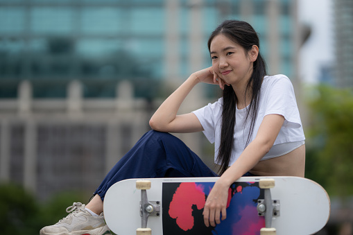 Cropped photo of a boy standing on the ground and stepping on the skateboard with the right foot