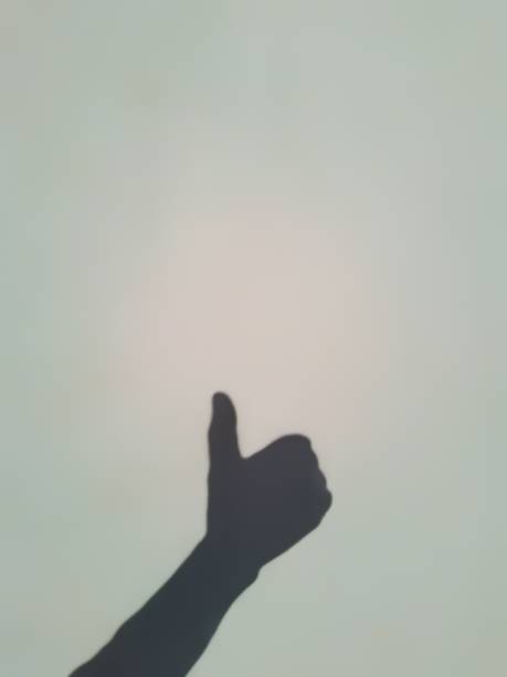 istock A human hand shadow shows a thumbs up or like gesture on the white background. Monochrome. 1861522373
