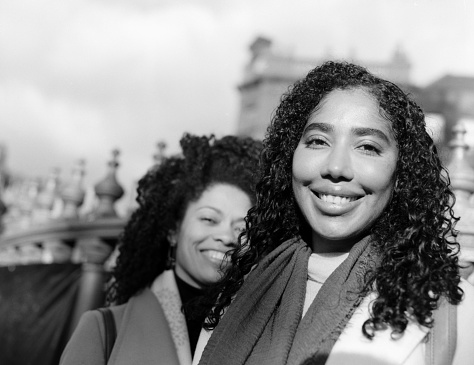 Two smiling female friends looking at camera in monochromatic analog portrait. The image is made with an old medium format analog film camera.
