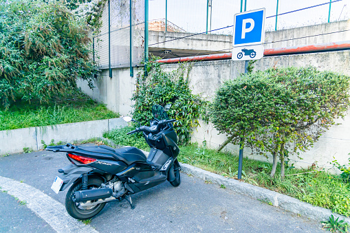 Paris, France - September 09, 2023 : Sign designating a motorcycle parking lot with a motor scooter parked