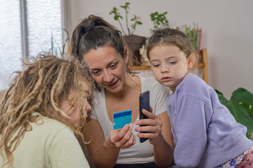 Empowering Financial Education at Home: Adult Mother Engages Young Children in Playful Financial Learning. Utilizing Financial Technology for a Fun and Informative Experience. Copy Space Available
