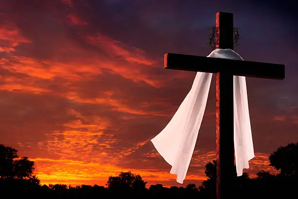 This dramatic sunrise lighting with large cross, burial cloth and crown of thorns makes a great Easter photo illustration of Jesus dying on the cross and rising again.