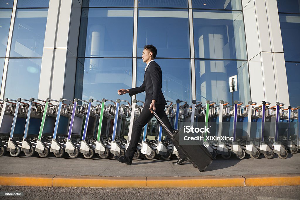 Viajero caminar rápido junto a la fila de los carritos de equipaje - Foto de stock de 18-19 años libre de derechos