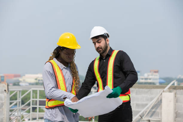 istock Foreman builder male and female at construction site. Group of foreman construction working at construction site, wearing safety uniform, helmet and holding blueprint structure 1861631673