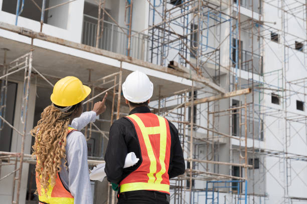 istock Foreman builder male and female at construction site. Group of foreman construction working at construction site, wearing safety uniform, helmet and holding blueprint structure 1861631676