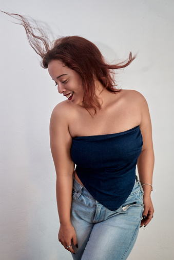 Girl standing with a blue blouse and jeans pants with the gray wall modeling