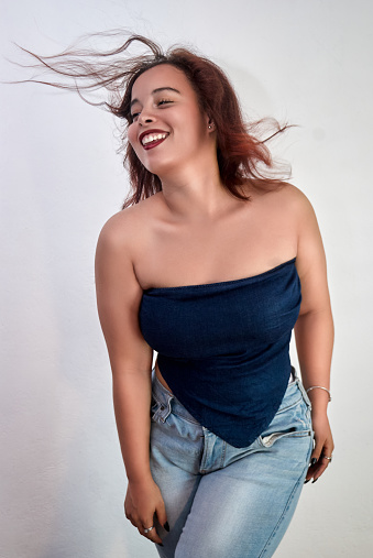 Girl standing with a blue blouse and jeans pants with the gray wall modeling