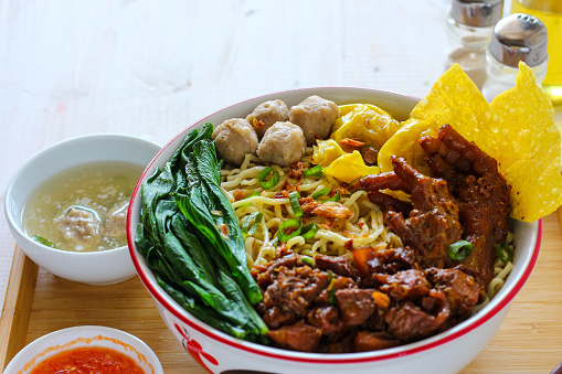 Mie ayam or chicken noodle. with vegetable, meatballs, and chicken topping.