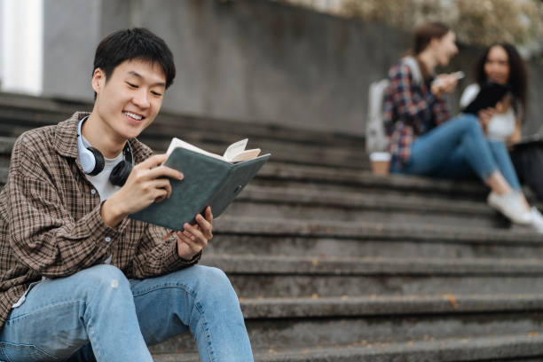 istock college student reading a book study on laptop prepare for the exam Or work on a group project while sitting on the steps of the university. 1861666766