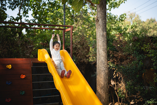 Five elementary-age children play during school recess or at a park setting. Playground equipment, slide. 