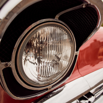 Close up of red classic car front headlight,