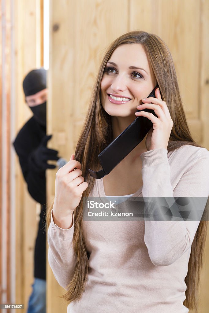 Burglary crime - culprit and victim Security - disguised burglar breaking in an apartment or office and standing behind the innocence victim Adult Stock Photo