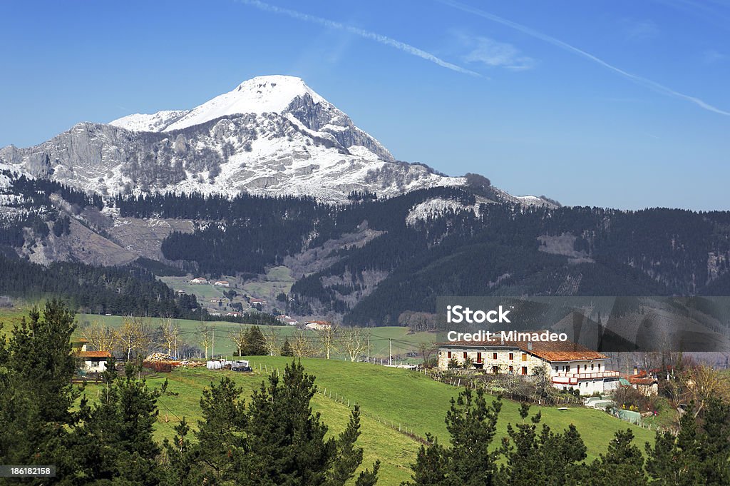 village in Aramaio valley, with snowy mountains. Basque Country village in Aramaio valley, surrounding by snowy mountains, in Basque Country Agricultural Field Stock Photo