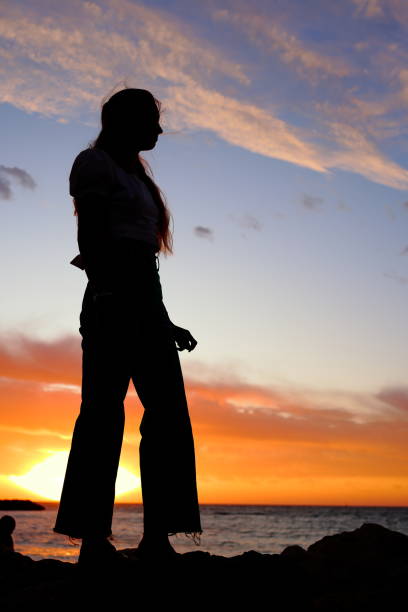 Silhouette of unrecognizable young woman at sunset