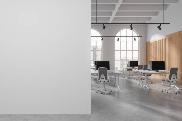 istock Elegant coworking interior with pc computers in row near window. Mock up wall 1861843757