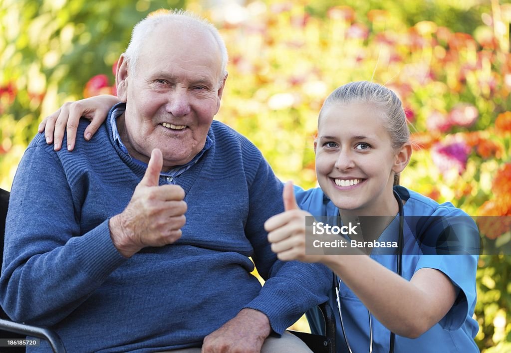 Thumbs up! Young happy doctor showing thumbs up with his elderly patient. Adult Stock Photo