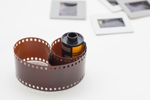 Roll of photographic film with slide mount frames on white background.