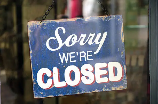 Photo of Old blue closed sign hanging in a shop window