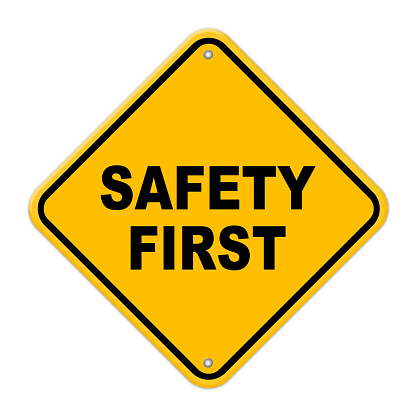 Yellow safety first road sign with rivets on a white background