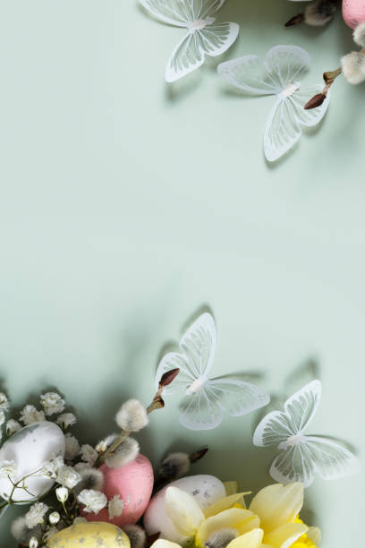 istock Butterflies and flowers, easter eggs and willow on green background with copy space. Easter greeting card template 1861910311