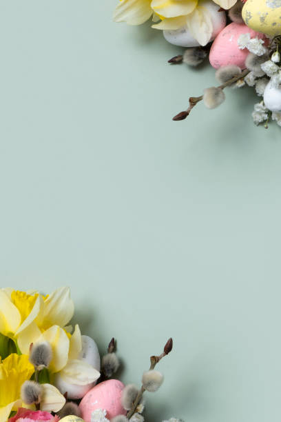 istock Daffodils, easter eggs and willow on green background with copy space. Easter greeting card template vertical format 1861910750