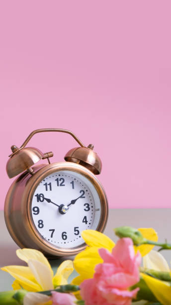 istock Alarm clock with spring flowers on color background. Spring time, daylight savings concept, spring forward. Copy space. 1861910833