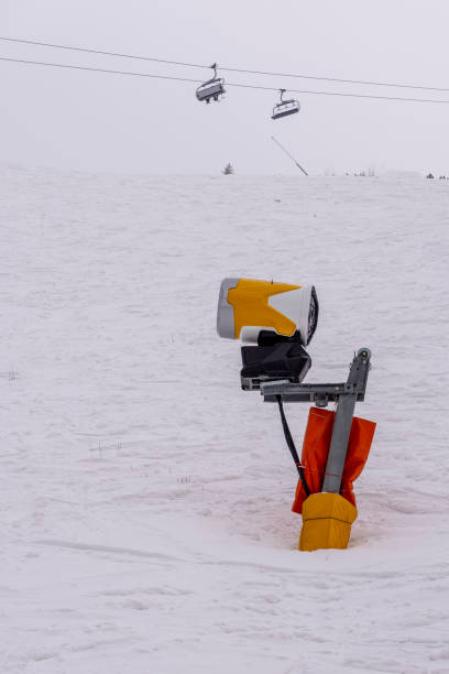 人工雪を作るためのオレンジ色の機械。人工人工降雪システム。冬の山の雪鉄砲。 人工雪を作るための高出力の雪砲です。 - mountain winter season machine snow making machine ストックフォトと画像
